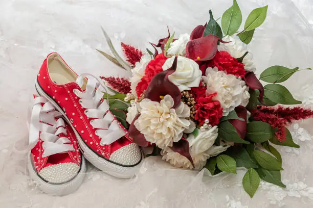 The bride's red canvas wedding shoes with her bridal bouquet.