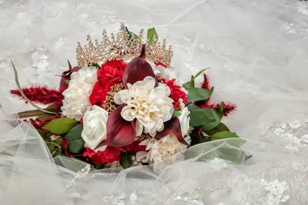 The bride's tiara against her wedding bouquet both laying on her wedding dress.