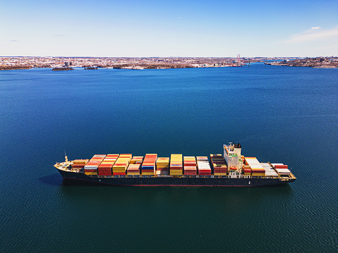 Aerial drone view of a container ship anchored in a harbor.