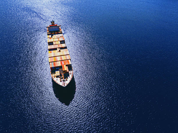 A stunning image of a freight ship on the ocean at sunset, with golden light rays breaking through the clouds and illuminating the water. The scene captures the serene beauty of the moment, blending the industrial silhouette of the ship with the natural drama of the sky. Perfect for maritime, travel, and nature photography themes.