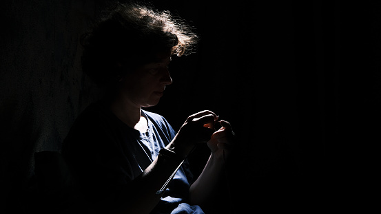 Senior woman is knitting in the darkness