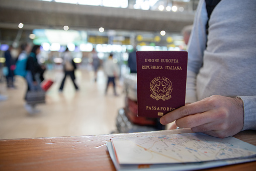 Primer plano de un pasaporte italiano sostenido por un viajero con un mapa al lado photo