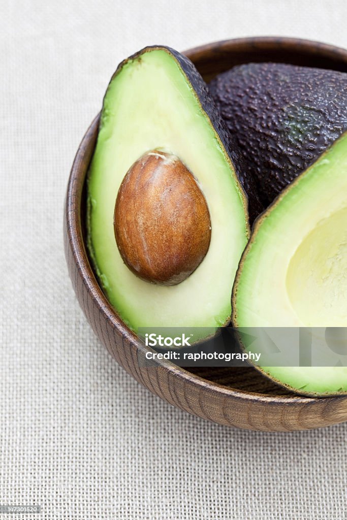 Fresh avocado Half an avocado in an old wooden bowl on a hessian cloth Avocado Stock Photo