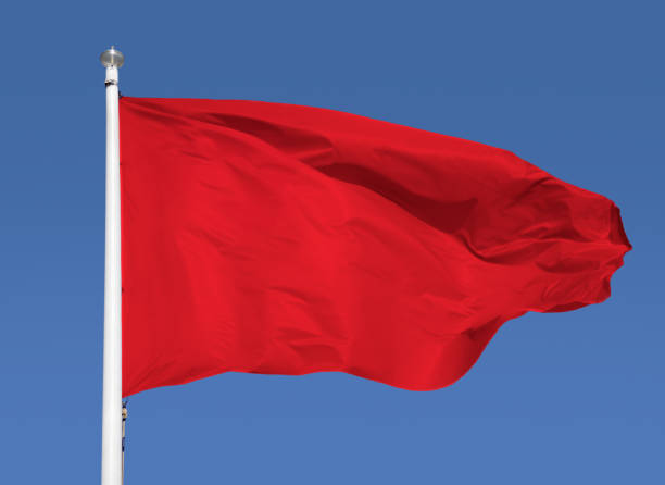 istock waving red flag over blue sky 1473015720