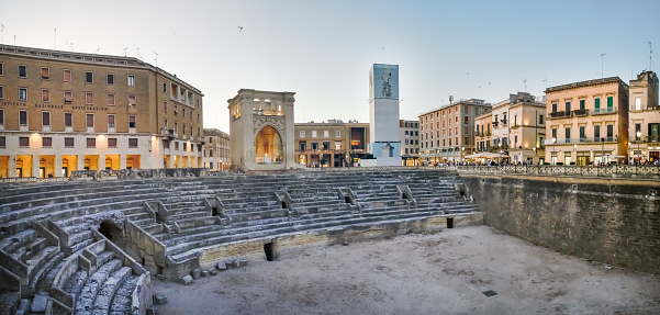 Lecce, Italy. 06 29 2019. Ruins of the amphitheater in the Sant Oronzo square and the old church of San Marcos in the center of the photo.