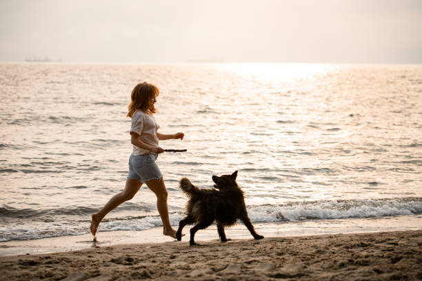 istock great view on woman running along sandy beach at water with her dog 1473016027