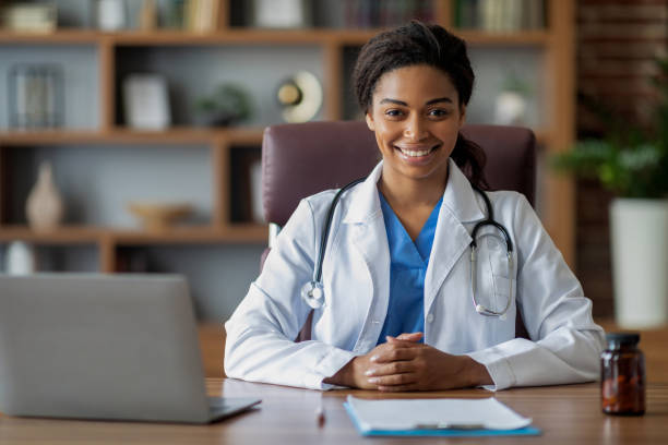 istock Doctor black lady in white robe with stethoscope at workplace 1473016452