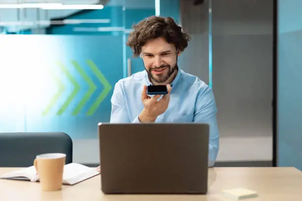 Photo of Smiling man working and talking on phone at office