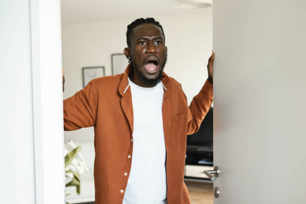 istock Shocked angry black man opening door, looking at something shocking and shouting, standing with open mouth 1473016529