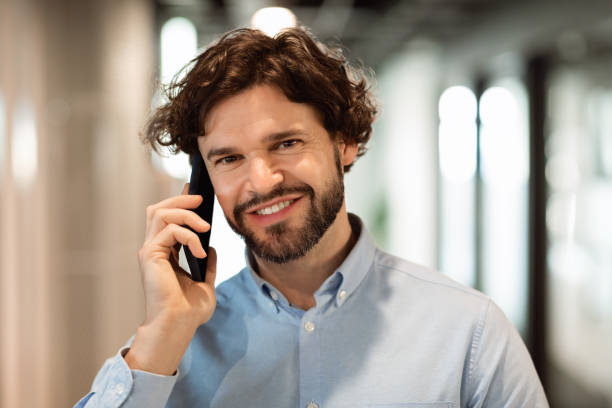 istock Smiling business man working and talking on phone at office 1473016543