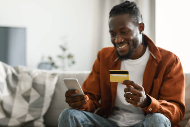 istock Internet mobile shopping concept. Excited african american man using cellphone and holding credit card, selective focus 1473017222