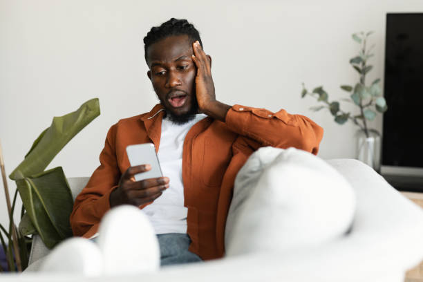 istock Oh no. Shocked black man reading bad message on smartphone, sitting on sofa, emotionally reacting to unpleasant news 1473017261