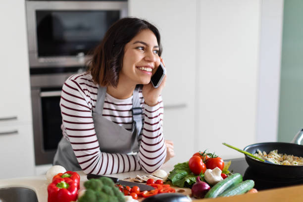 istock Positive young arab woman having phone conversation while cooking 1473017481