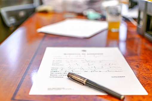 Text in French and a pen placed on the wooden desk.  Selective focus with blur background