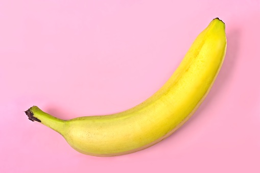 Banana against a bright pink background. Horizontal image.