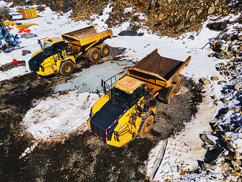 Aerial drone view of off-highway dump trucks on a construction site.