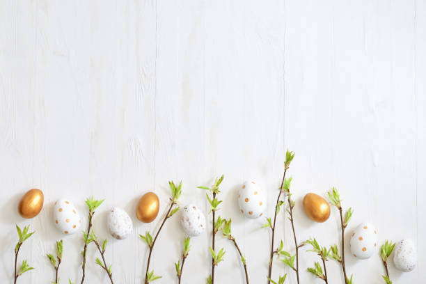istock Branches with green leaves and easter eggs on a light background. Happy easter flat lay concept 1473023440