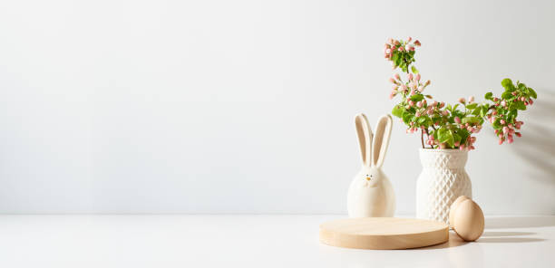 istock Empty round wooden podium for product presentation. Spring flowers in a vase and easter eggs on a light background. 1473023448