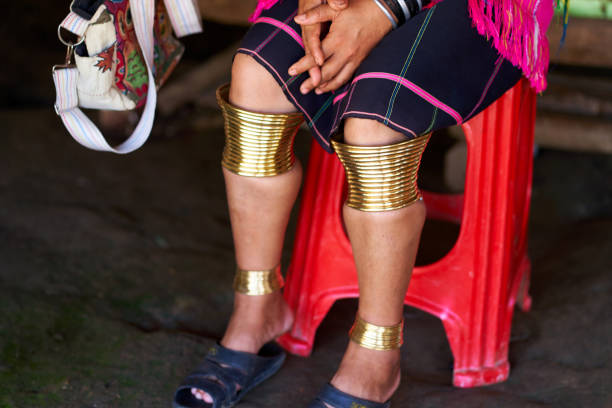 Long Neck tribe woman adorned with rings on her limbs and large ear tunnels Woman from the Long Neck tribe, wearing traditional brass rings on her limbs and large ear tunnels. The intricate details of her jewelry create a sense of cultural richness and tradition kayan neck rings stock pictures, royalty-free photos & images