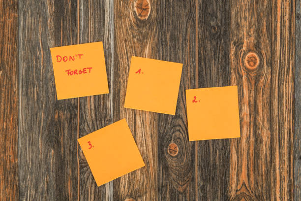 Orange ticky notes on a brown wooden background with text don't forget and three empty sticky notes with numbers from 1 to 3.