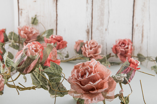 Artificial romatic roses on white wooden background