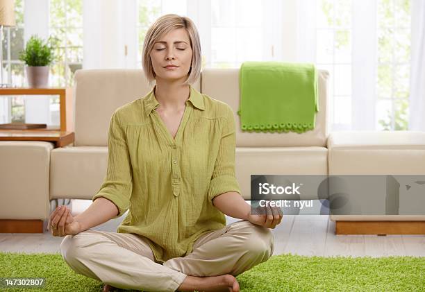 Photo libre de droit de Femme Faisant Yoga Méditation À La Maison banque d'images et plus d'images libres de droit de Canapé - Canapé, Méditer, Yeux fermés