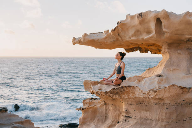 istock Young woman meditating on a cliff overlooking an ocean 1473029009