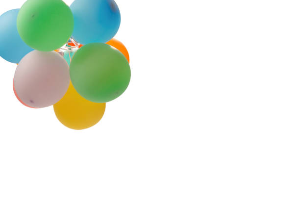 Multicolored balloons are flying against a cloudy sky in a low-angle view, creating a whimsical and vibrant scene.