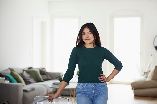 Portrait of attractive young asian woman standing at home. Female with standing confidently in living room at home.