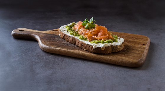 Studio photo of a toast with cheese, salmon and avocado on a wooden surface