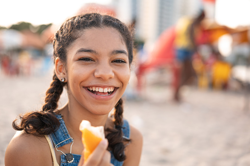 Portrait of teen girl eating popsicle at the beach