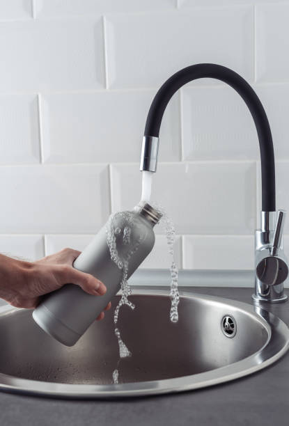istock Hand holding a metal bottle under running water. 1473038866