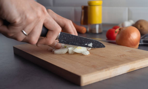 istock Hands with knife cutting an onion on a cutting board 1473039063