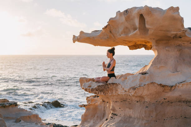 海を見下ろす崖の上で瞑想する若い女性 - vitality nature beauty in nature beauty ストックフォトと画像