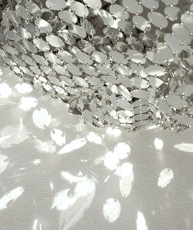 Mirror chain mail and sunbeam reflections on a light background.