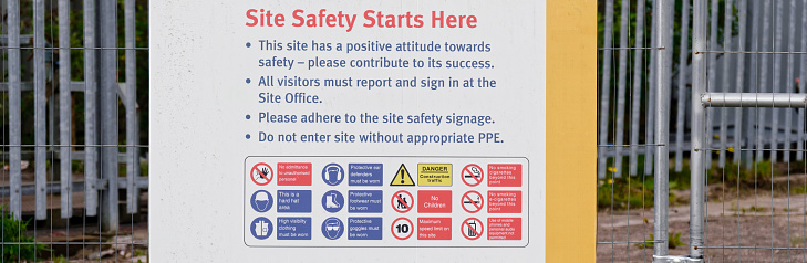Construction site health and safety message rules sign board signage on fence boundary UK