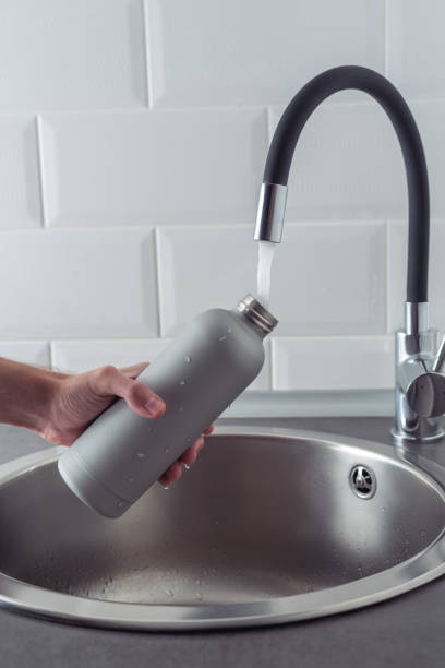 istock Hand holding a metal bottle under running water. 1473040550