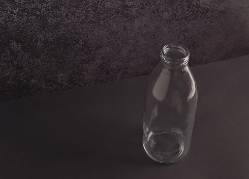 Colorless transparent glass bottle on a dark background.