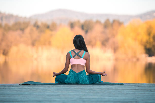istock Young Asian Woman Meditating By a Waterfront 1473042116
