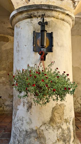 istock Basket with small red flowers is suspended from an old thick column 1473043061