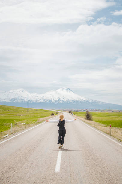 istock Young woman walks down centre line on road 1473043475