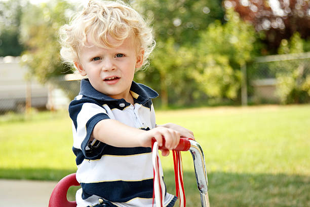 Young boy riding tricycle. stock photo