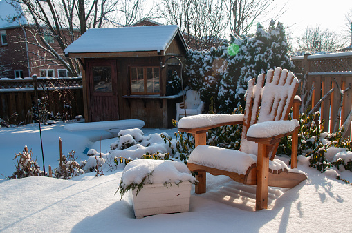 A backyard with a muskoka chair and a cabana covered in snow