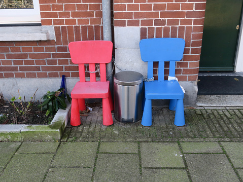 a blue and red childrens chair and a dustbin in front of a house