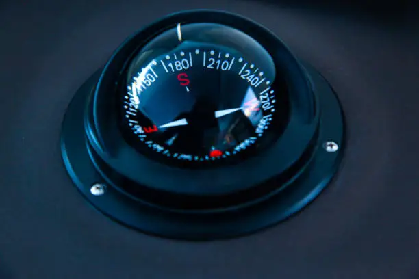 Marine gyrocompass mounted on the black hull of the yacht, close-up. Yacht navigation equipment.