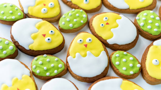 istock Easter background with funny sugar biscuits. Cute chickens in the eggshell iced butter biscuits. Creative ideas of cookie icing with bright glaze. Easter banner in yellow and green tones. 1473046947