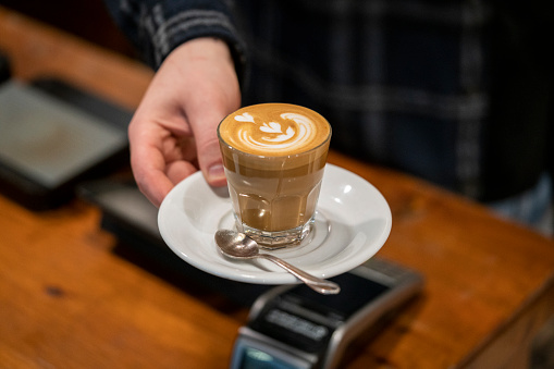 Barista serving cup of latte coffee