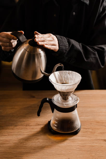 istock Pour over filter coffee alternative brewing method. Pouring hot water over roasted and ground coffee beans contained in paper filter. 1473047276