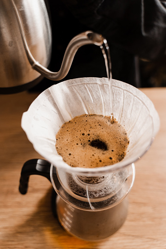 Pour over filter coffee alternative brewing method. Pouring hot water over roasted and ground coffee beans contained in paper filter