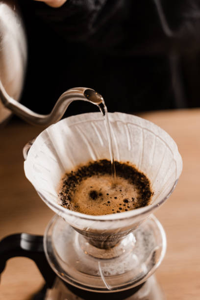 istock Close-up pour over filter with ground coffee in the funnel in focus. Drip filter coffee brewing. Pour over alternative method of pouring water over roasted and ground coffee beans contained in filter. 1473047288